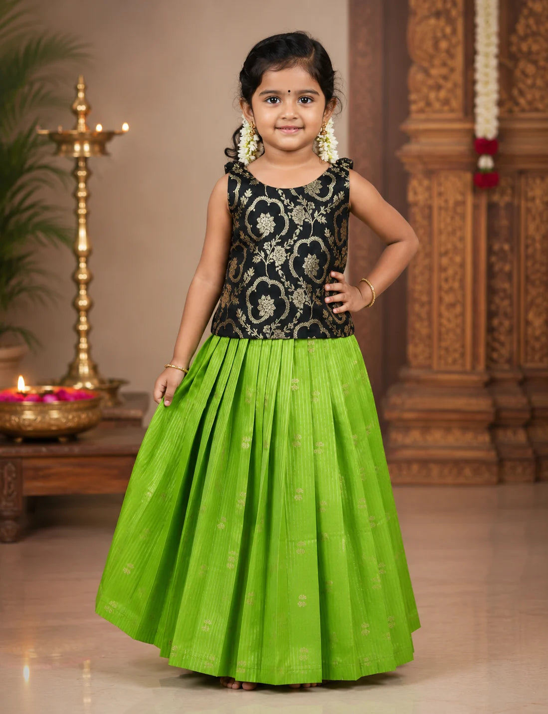 Young girl in a black floral top and green skirt standing indoors with decorative background