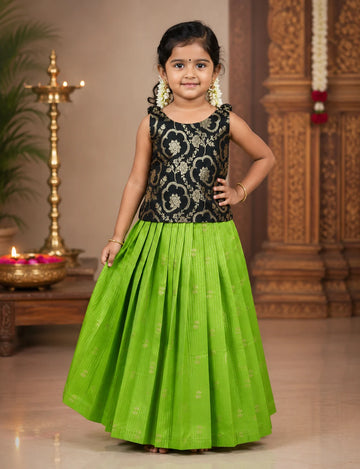 Young girl in a black floral top and green skirt standing indoors with decorative background