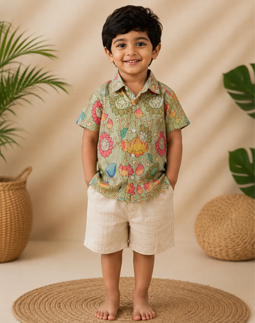 Child wearing a floral shirt and beige shorts standing against a beige background with plants.