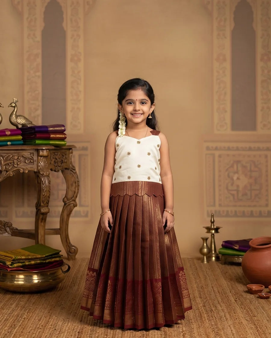 Young girl in a traditional outfit standing in a decorated room with ornate wall designs.