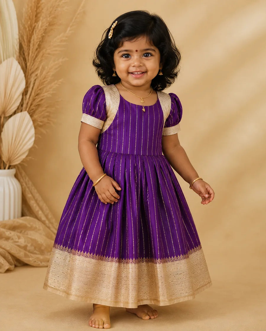 Child wearing a purple and gold traditional dress against a beige background
