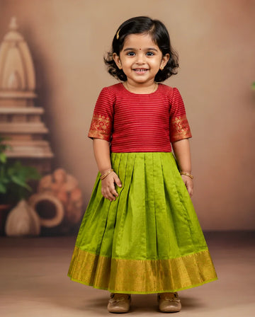 Child wearing a red top and green skirt with gold accents against a brown background