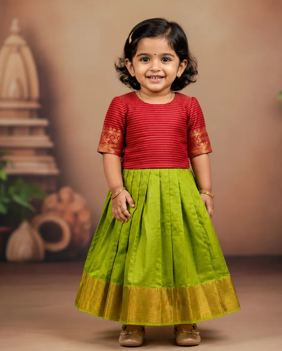 Child wearing a red top and green skirt with gold accents against a brown background