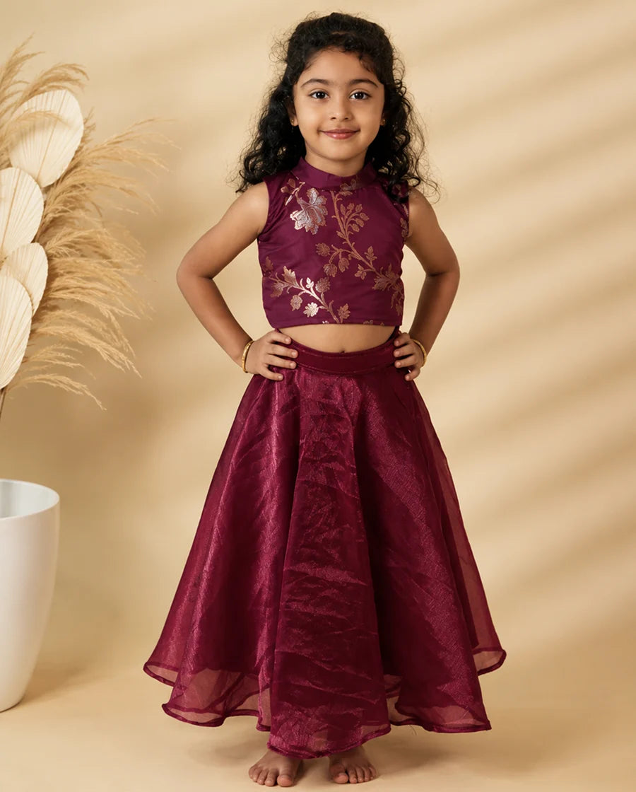 Young girl wearing a maroon traditional outfit with floral embroidery on a beige background