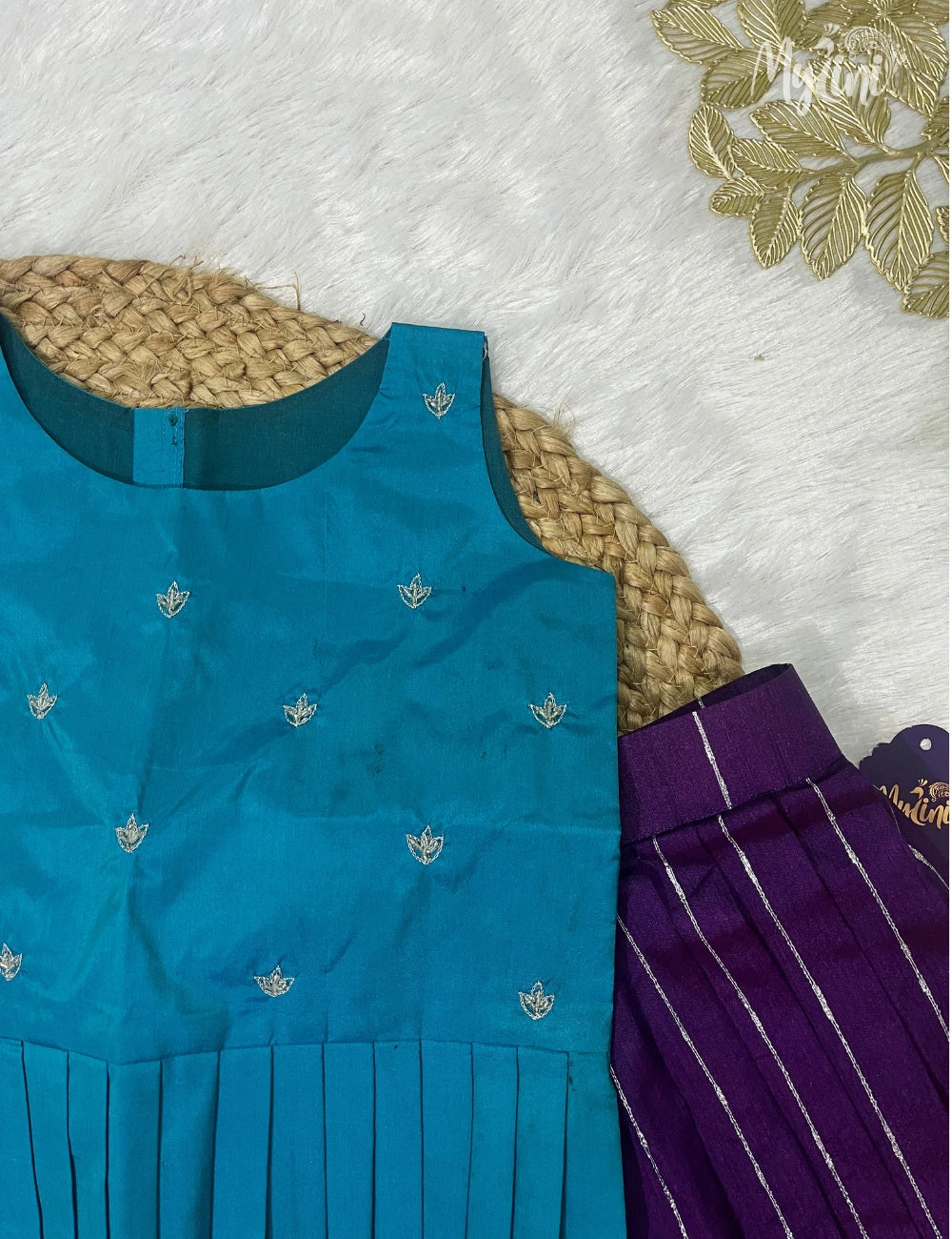 Young girl in a blue top and purple skirt standing on a brown floor with decorative elements.